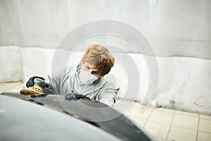 Mechanic grinds car part for painting. Car body work auto repair paint after accident