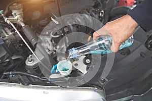 Mechanic hand fill fresh water into windscreen in car engine room