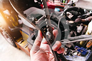 A mechanic hand holding a car timing belt.