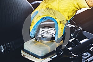 The mechanic hand is open or close the cap of the power steering fluid to check the hydraulic fluid level