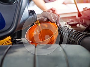 Mechanic hand pouring fresh  engine oil through orange funnel into the car engine