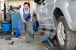 Mechanic hands in blue uniform pushing a black tyre