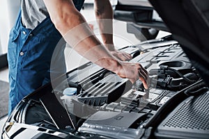 Mechanic hands checking up of serviceability of the car in open hood, close up.