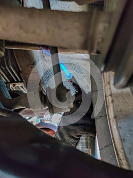 A mechanic heats an old bolt in a car with a blow lamp to unscrew it. A man in a salon is repairing a broken car