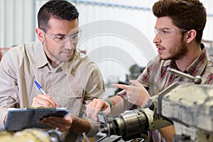 mechanic helping apprentice to fix engine