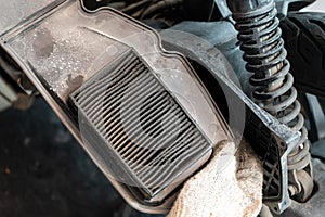 Mechanic holding dirty air filter of motorcycle at garage .dirty air filter will impede airflow. maintenance, repair motorcycle