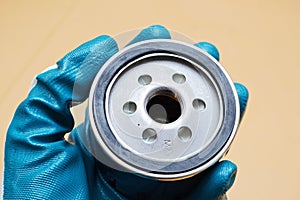 Mechanic holding an oil filter in hand with blue gloves