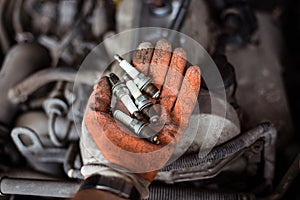 Mechanic holding old broken car spark plugs