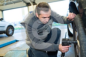 mechanic holding pressure gauge for checking tire pressure