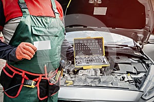 Mechanic holding tool box near broken car