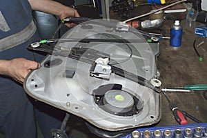 A mechanic holds a car door panel in his hands