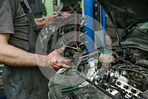 Mechanic holds dismantled part of car engine