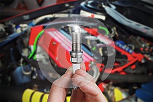 Mechanic holds a spare part spark plug in hand