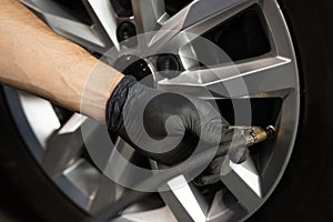 Mechanic inflating a car tire. Gas pumping of a car wheel. Car tire inflation. Car tire pressure check using air