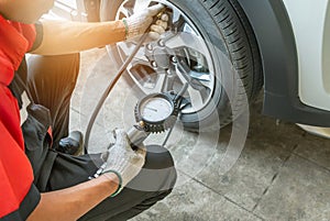 mechanic inflating put air into the tyre and checking air pressure with gauge pressure