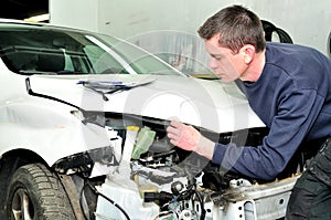 Mechanic inspecting car body damage at auto repair shop service