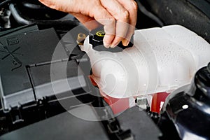 mechanic inspects the expansion tank with pink antifreeze. Vehicle coolant level in the car's radiator system. auto parts photo