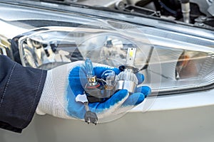 Mechanic installing changing modern halogen headlight bulb