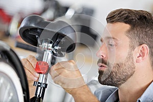 mechanic installing saddle on bicycle in workshop photo