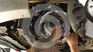 Mechanic installs clutch kit in car. Professional replaces release bearing, cover, disk on vehicle. Auto repair shop