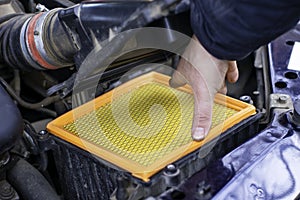 the mechanic installs a new filter element in the car& x27;s air filter