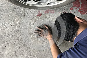 Mechanic laying behind car and looking under car