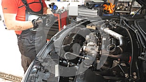 Mechanic makes an car maintenance in auto service. Professional repairman checking automobile motor at workshop. Man