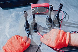 Mechanic man with digital multimeter testing ignition coil