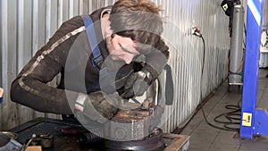 Mechanic man grind rusty metal with rasp tool in garage.