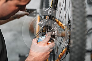 Mechanic man Hands, Spraying Oil To A Bike Chain. Bicycle maintenance.