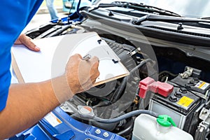 Mechanic man holding clipboard and check the car