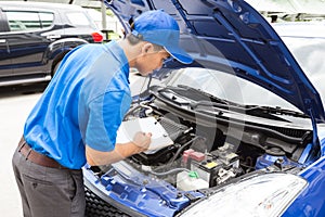 Mechanic man holding clipboard and check the car