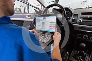 Mechanic man with laptop making car diagnostic