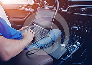 Mechanic man with laptop making car diagnostics at auto service