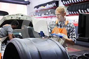 Mechanic man with laptop making car diagnostics at service