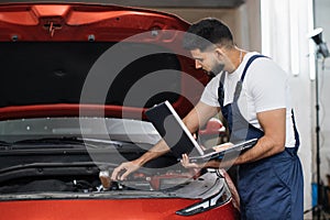 Mechanic man mechanic manager worker using a laptop computer checking car