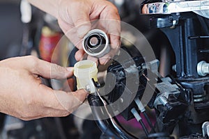 Mechanic man open cap and Check Brake Fluid on Motorcycle in garage, motorcycle maintenance and service and repair concept