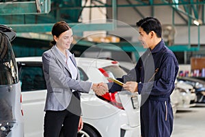 Mechanic man shaking hands with customer at the repair garage. Auto mechanic shaking hands with young woman client, Car repair and