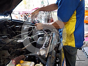 Mechanic man in uniform repairing car in garage. Auto repair service.
