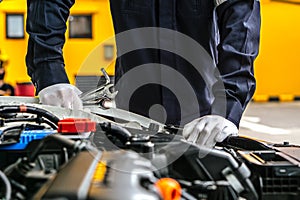 Mechanic man working on the engine of the car in the garage.Car service and maintenance,Repair service.Checks car engine under the