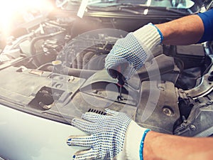 Mechanic man with wrench repairing car at workshop