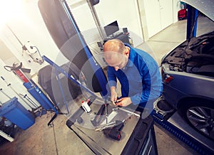 Mechanic man with wrench repairing car at workshop