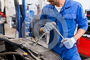 Mechanic man with wrench repairing car at workshop