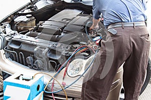 Mechanic with manometer filling gas into auto vehicle air-condit