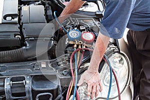 Mechanic with manometer inspecting auto vehicle air-condition co