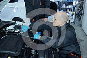 mechanic men with wrench repairing car at workshop.