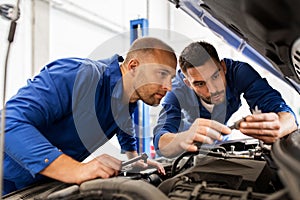 Mechanic men with wrench repairing car at workshop