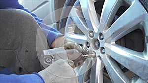 Mechanic mounting a wheel and tightening wheel nuts on a vehilce in a auto service