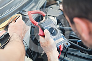 Mechanic with a multimeter testing car engine. Car service