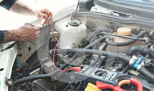 Mechanic with a multimeter testing car engine. Car service